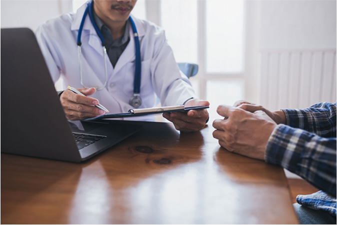 A doctor sitting with a patient in a bright office, discussing findings